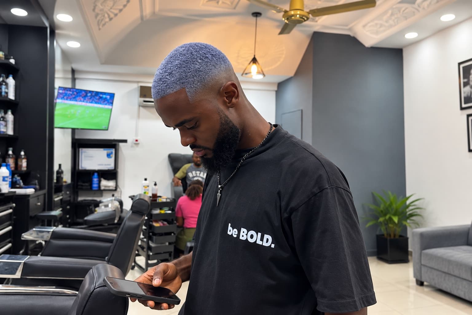 Ice-blue dyed waves over a low fade with a full beard, standing in the shop